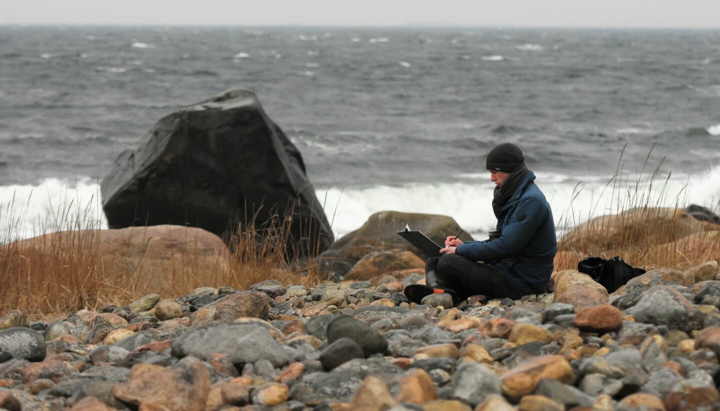Axel Thorenfeldt fra Kirkøy bruker Hvaler-naturen som inspirasjon til akvarellbildene sine. Her sitter Axel i fjæresteinene og maler mens stormkastene pisker i maleblokka